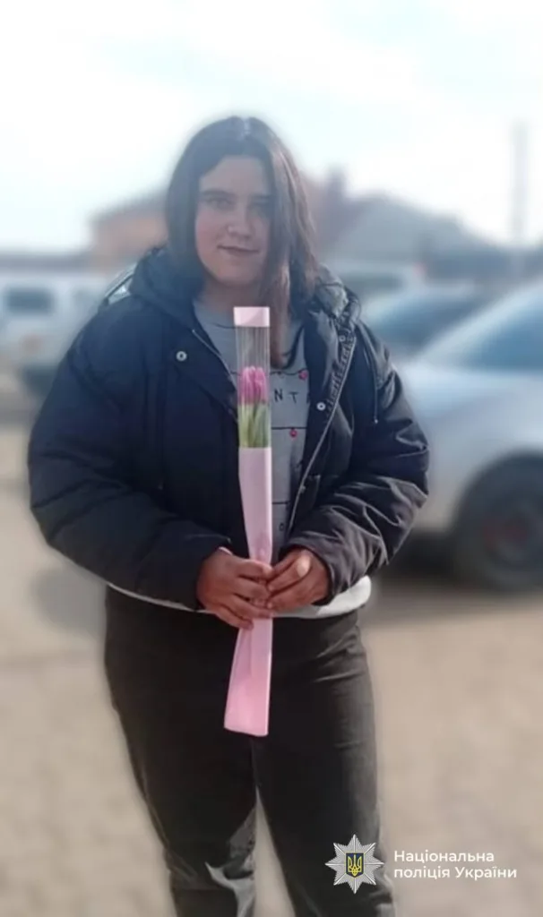 Людина тримає рожеву квітку на вулиці