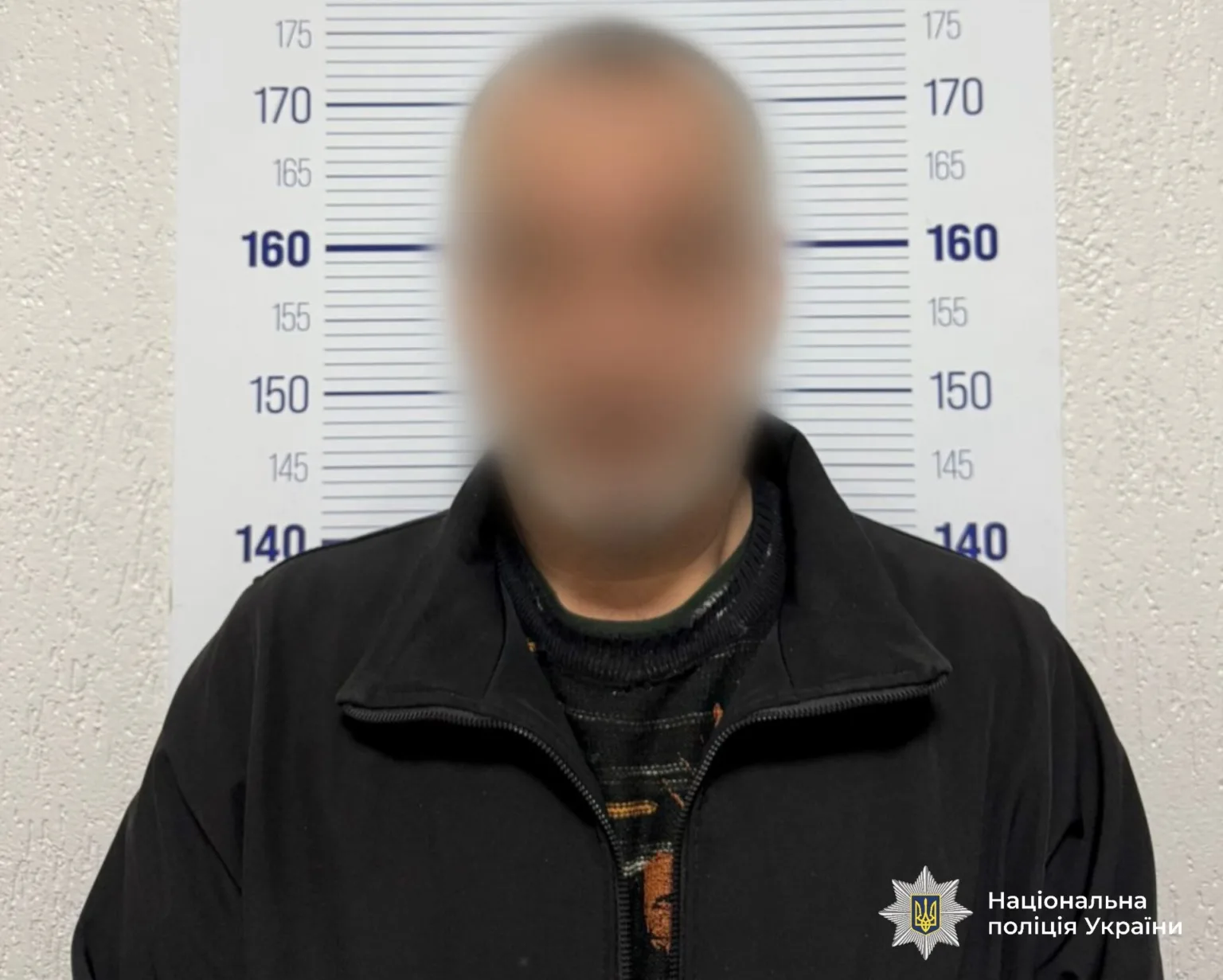 Затримана особа перед фоном поліції України