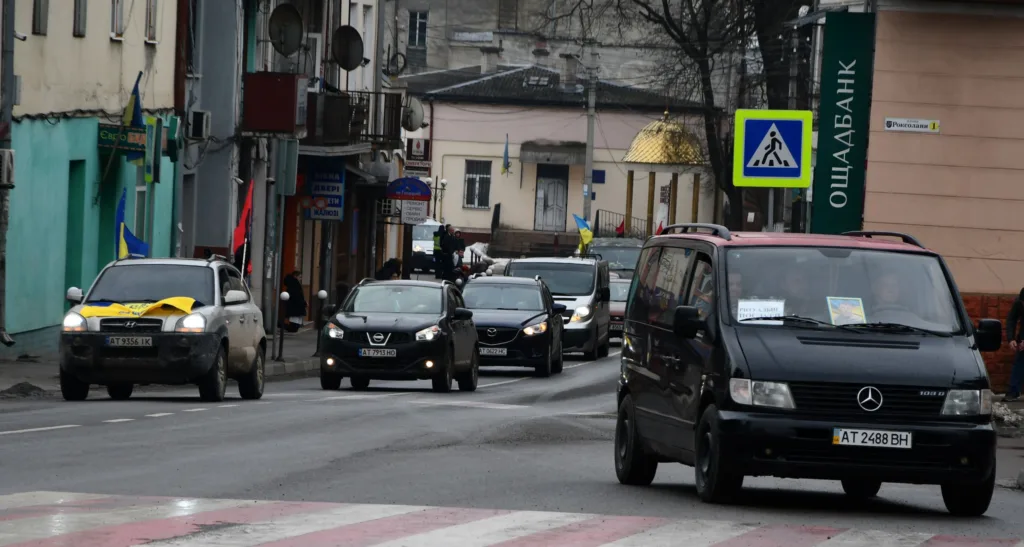 Автоколона з українськими прапорами на міській вулиці