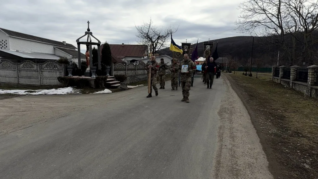 Військові йдуть із прапорами селом України