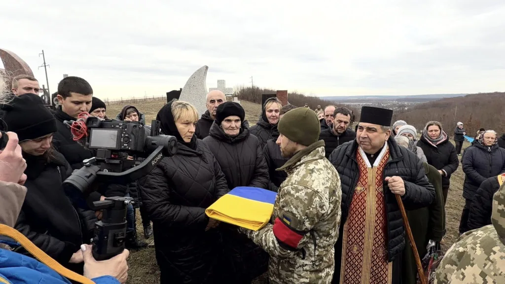 Військовий передає прапор родині на похороні