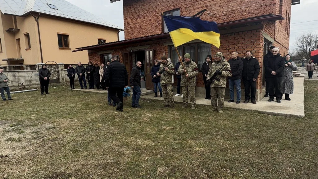 Військові з українським прапором перед будинком