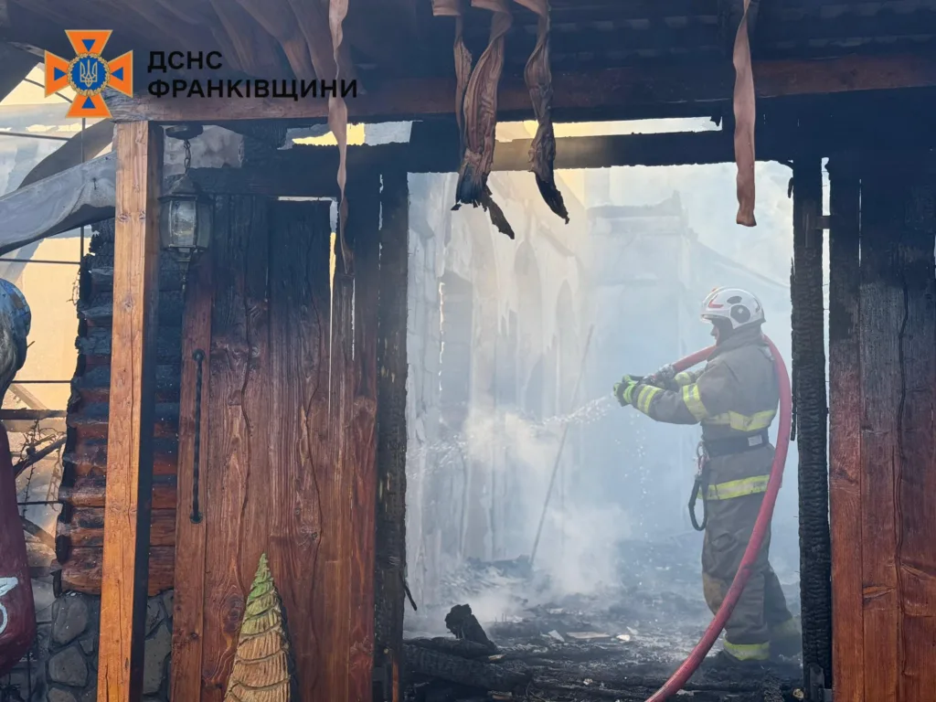 Пожежник гасить вогонь у згорілій будівлі