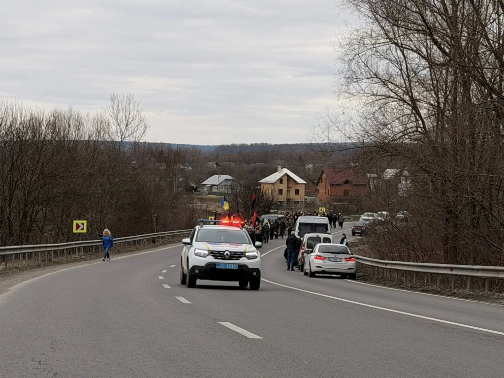 Поліцейський автомобіль супроводжує колону на сільській дорозі