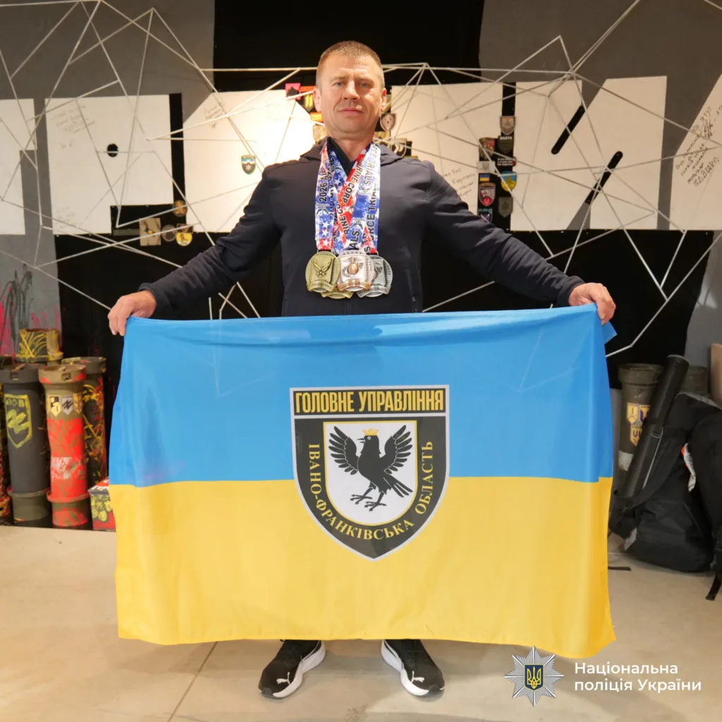 Поліцейський з медалями тримає прапор Івано-Франківщини