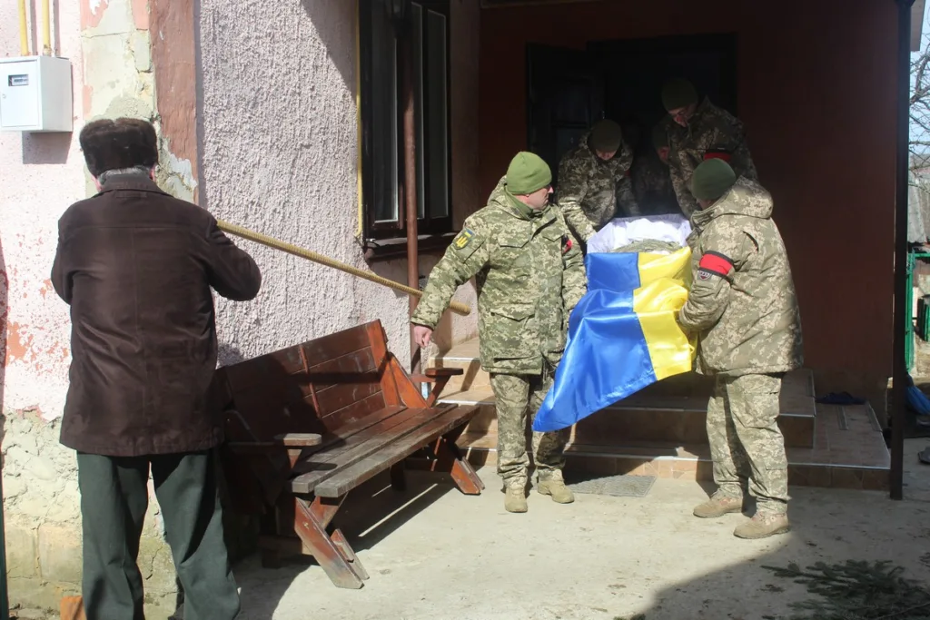 Військові несуть труну з українським прапором