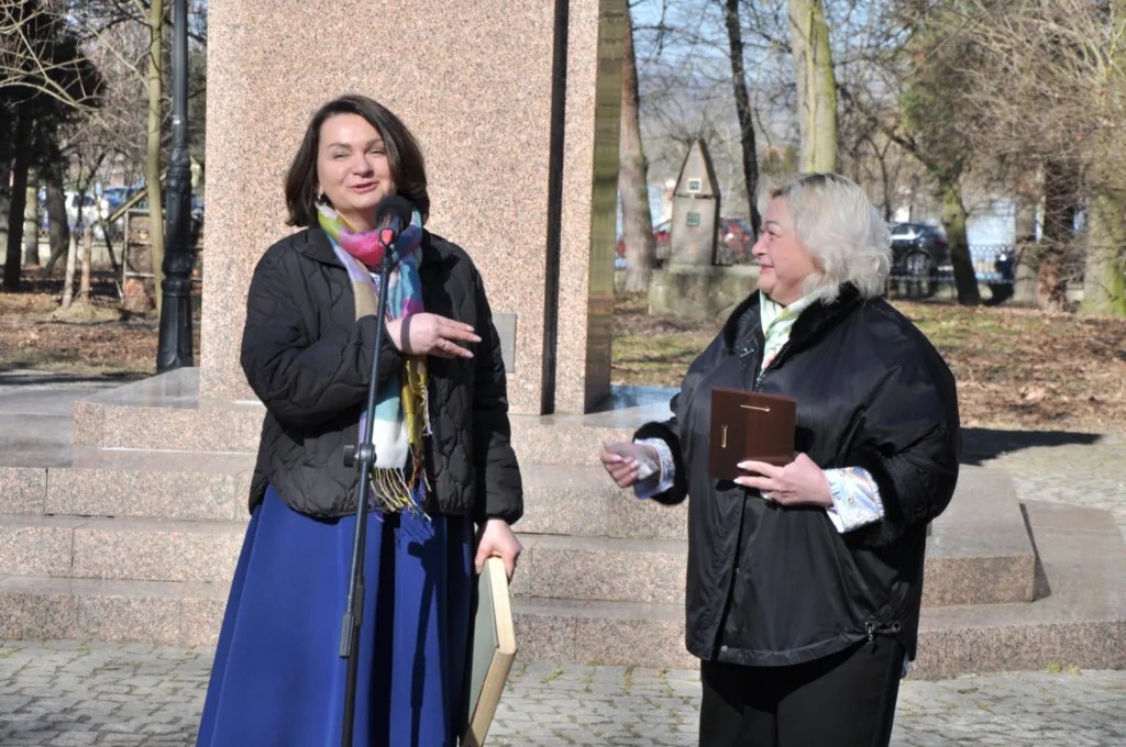 Дві жінки виступають біля пам'ятника на вулиці