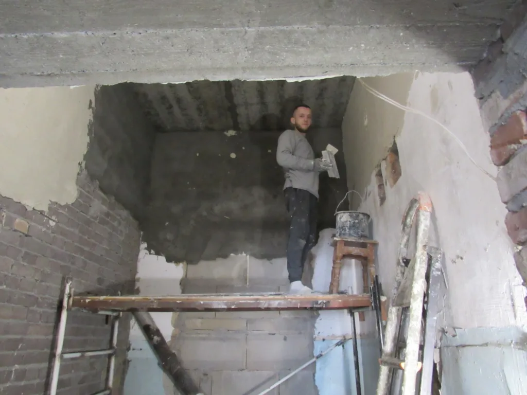 Робітник штукатурить стіну в приміщенні