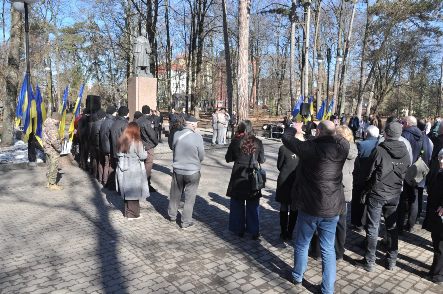 Люди на мітингу біля пам’ятника з українськими прапорами