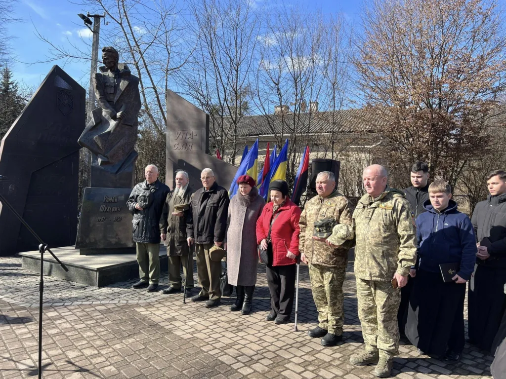 Люди біля пам’ятника з прапорами на вшануванні