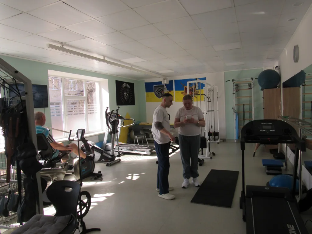 Люди тренуються у спортивному залі з обладнанням