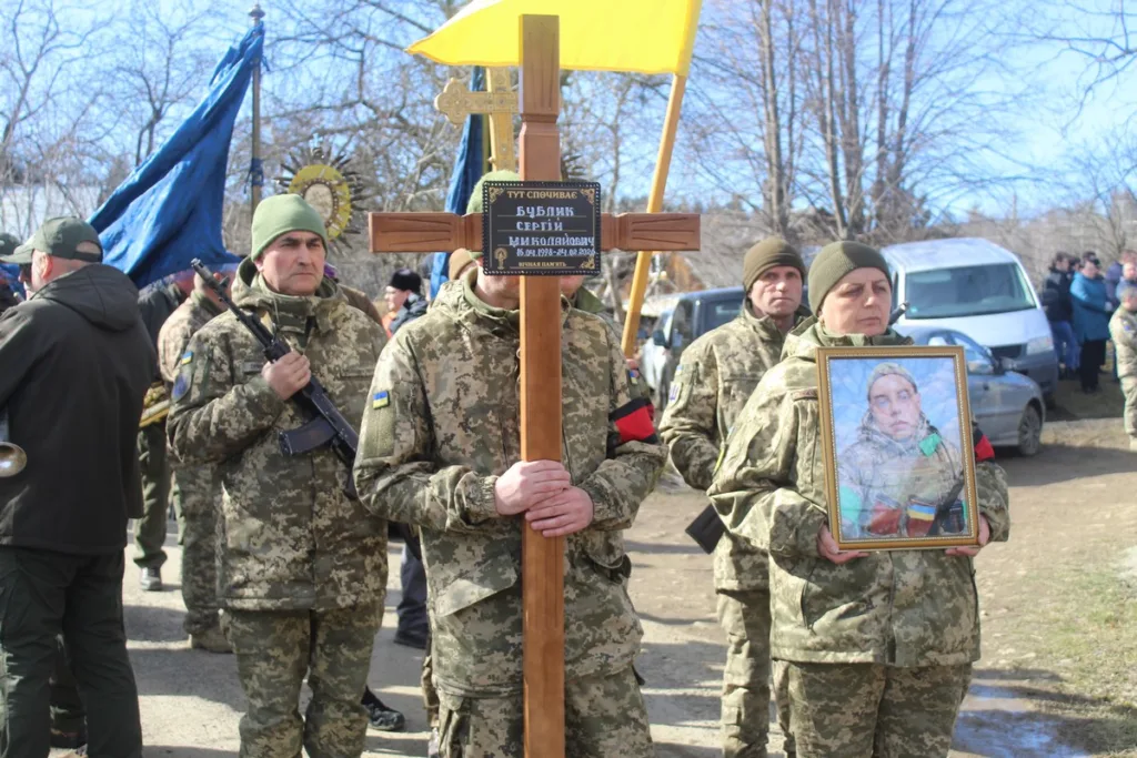 Військові несуть хрест і портрет загиблого героя