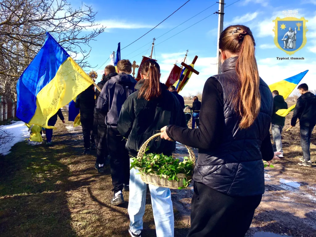 Люди з українськими прапорами йдуть селом