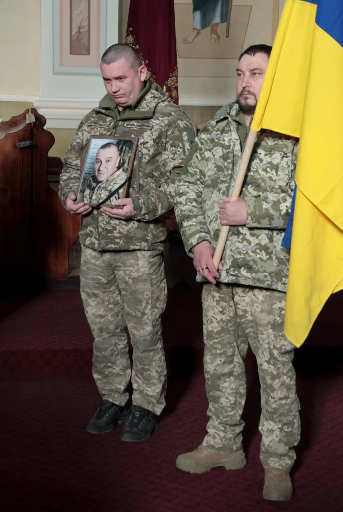 Військові тримають прапор України та портрет загиблого