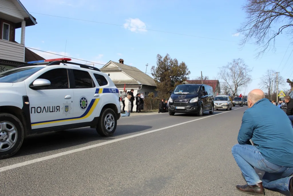 Поліційна машина на вулиці з людьми поруч