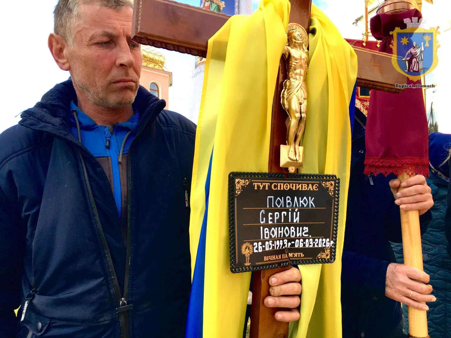 Чоловік тримає хрест із жовто-блакитною стрічкою