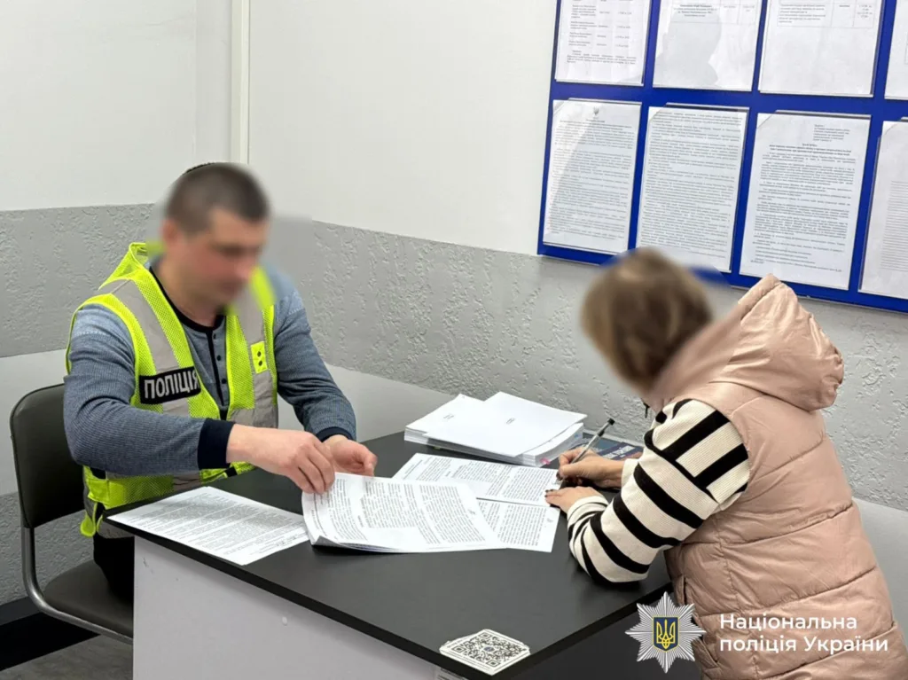 Поліцейський допомагає жінці заповнити документи