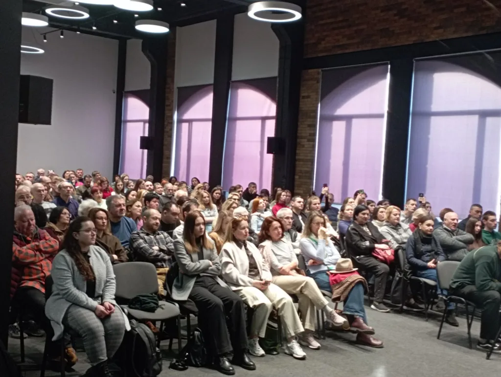 Люди слухають лекцію у великій залі