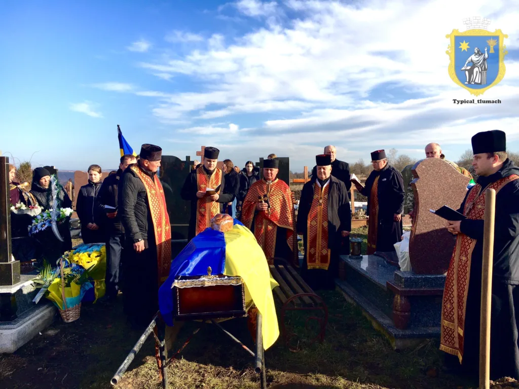 Похоронна церемонія з українським прапором на цвинтарі