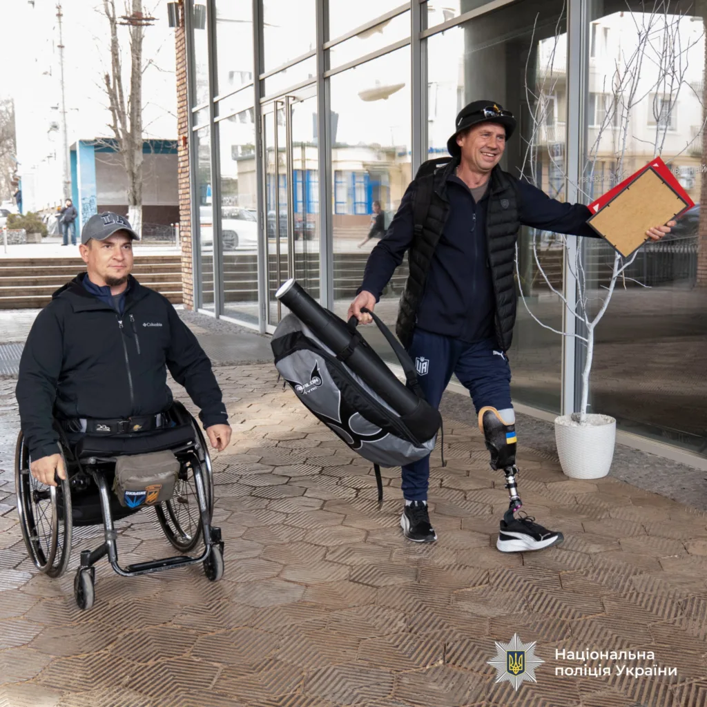 Двоє чоловіків з протезом та інвалідним візком йдуть