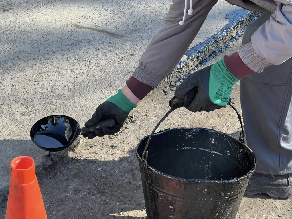 Працівник ремонтує асфальт гарячим бітумом