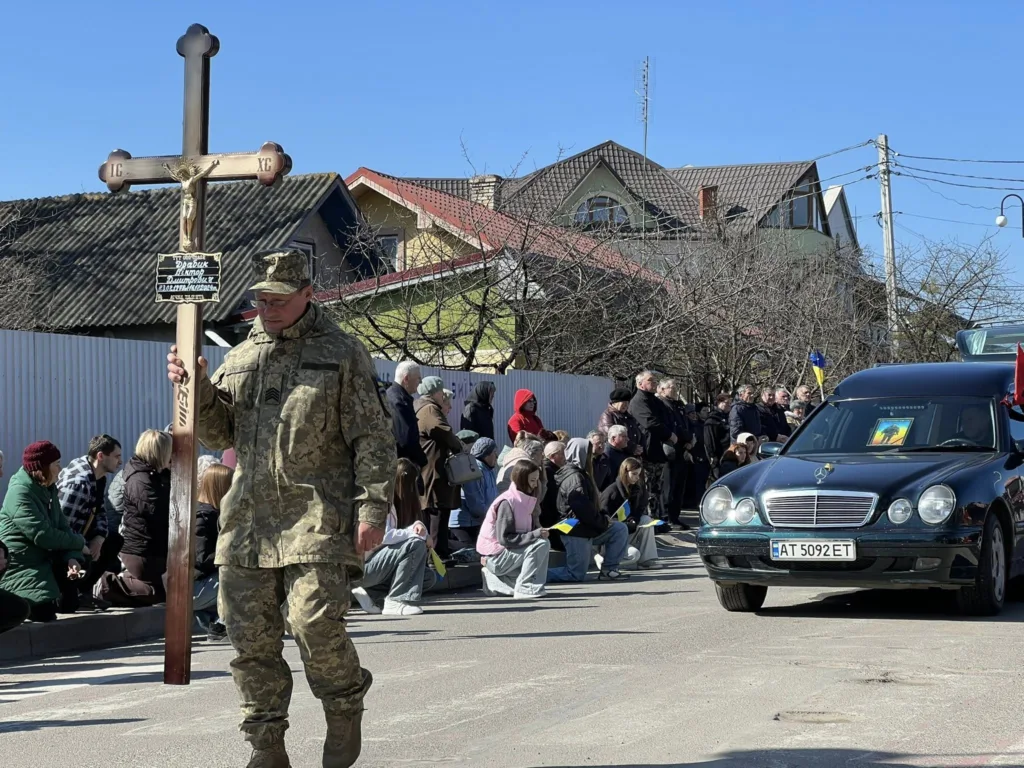 Військовий похорон у місті, люди стоять на колінах