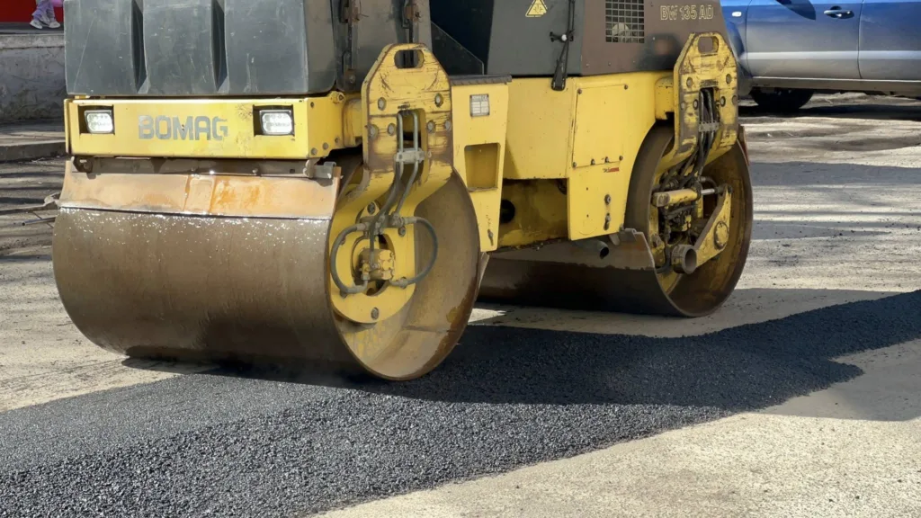 Асфальтний коток ущільнює нове дорожнє покриття