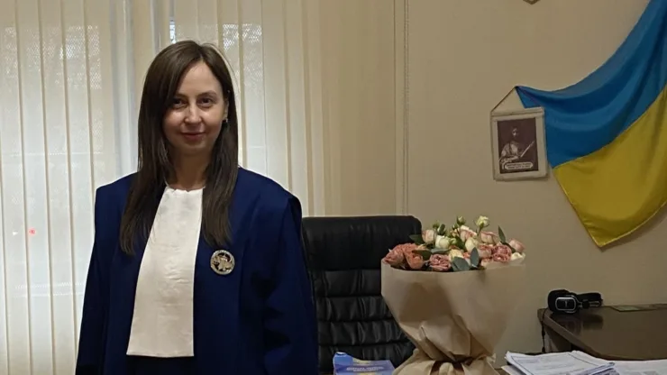 Жінка у синій мантії стоїть в офісі