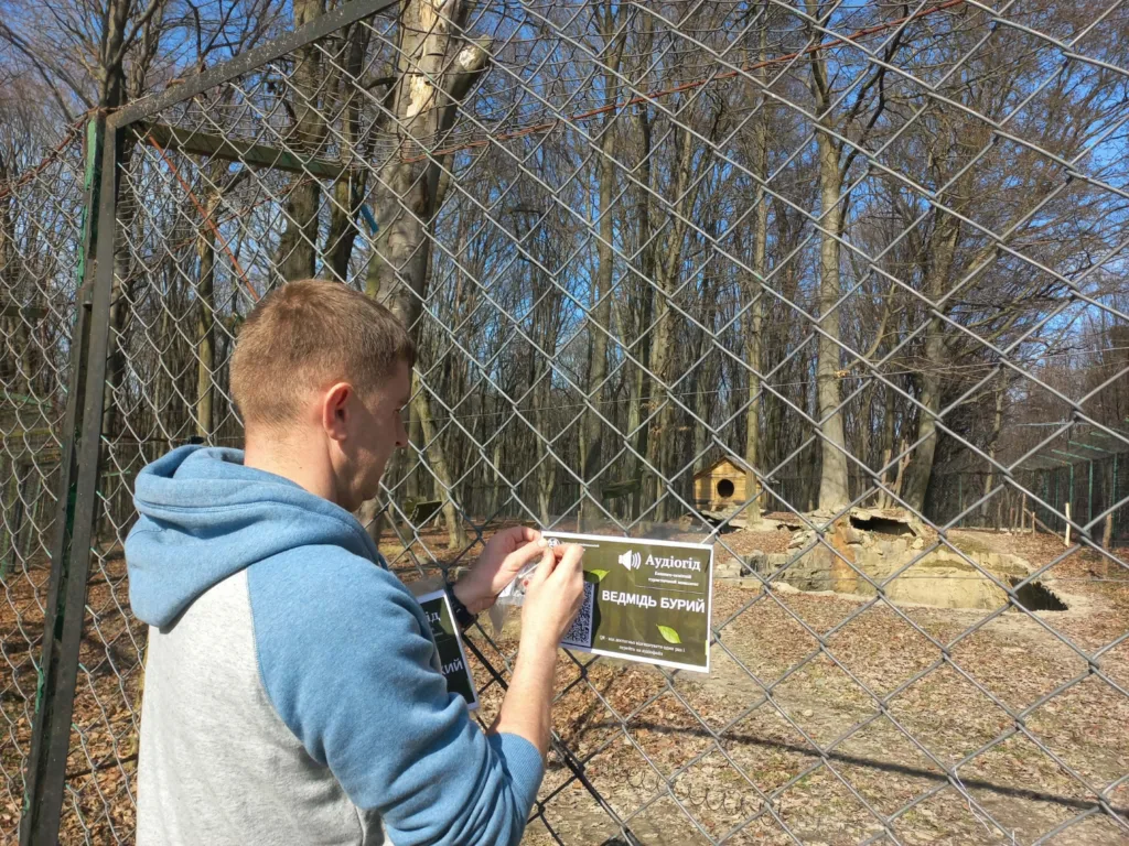 Чоловік кріпить табличку біля вольєра ведмедя