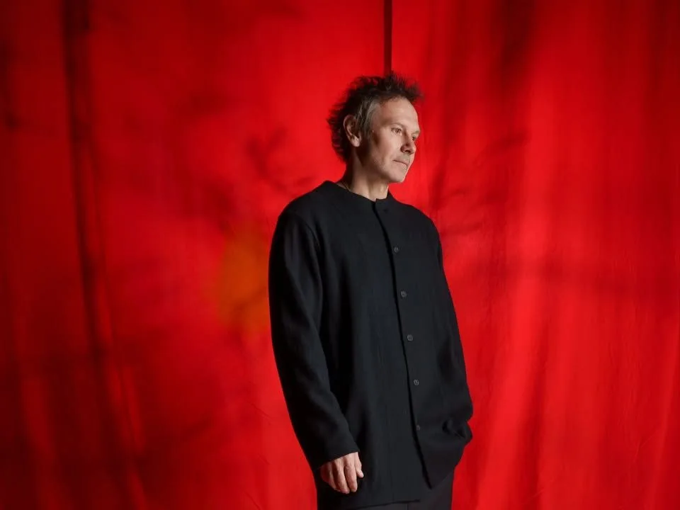 Людина в чорному одязі перед червоною завісою