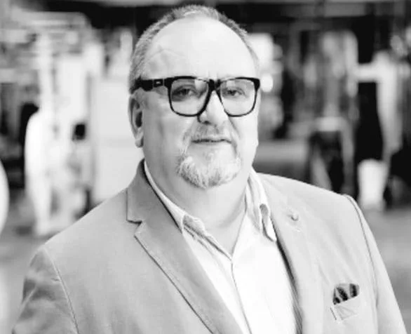 Чоловік у піджаку та окулярах у приміщенні