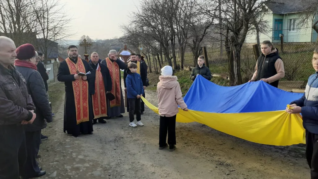 Священники та діти тримають український прапор