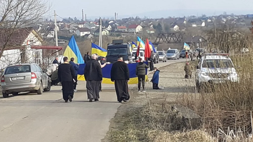 Люди йдуть з великим прапором України дорогою