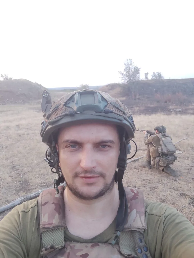 Військовий у касці на полі з іншим солдатом