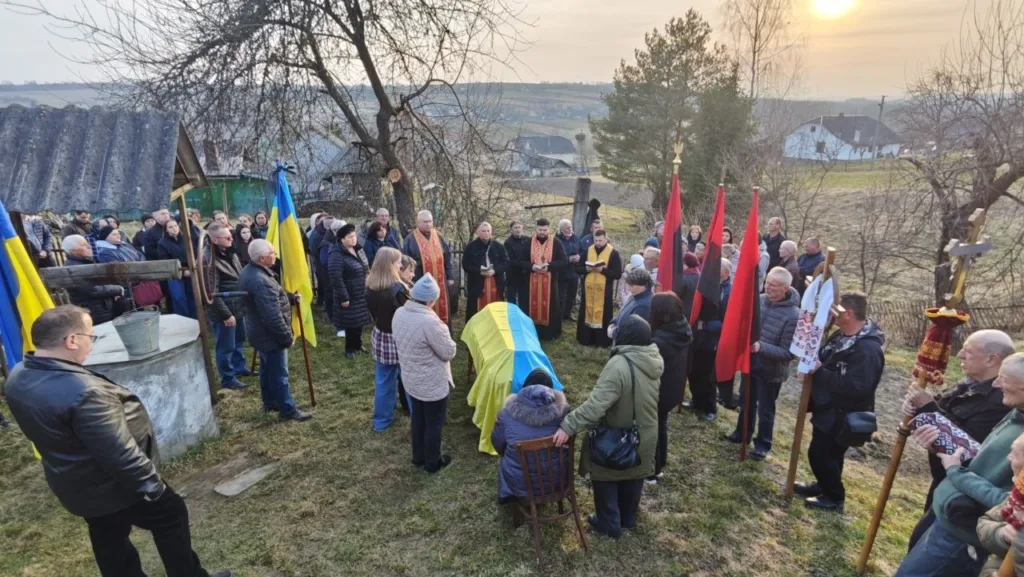 Похоронна церемонія з українськими прапорами на подвір’ї