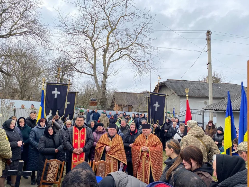 Похоронна церемонія з українськими прапорами та священниками