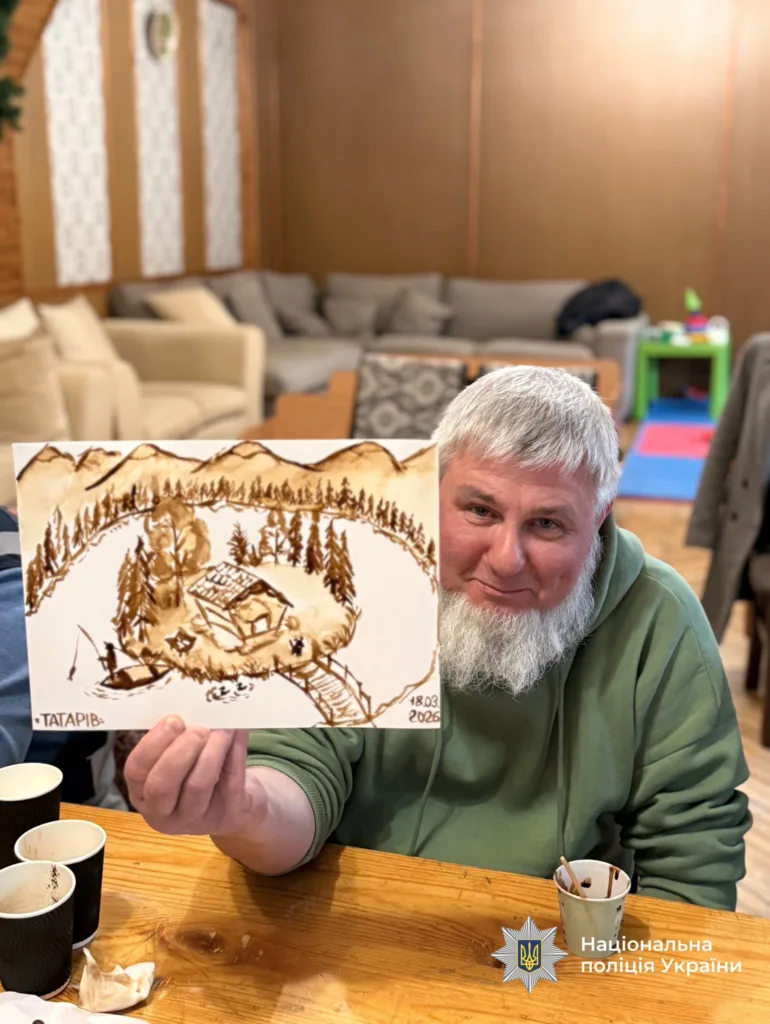 Чоловік показує малюнок з хатою в горах