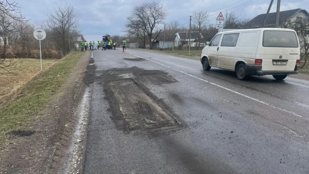Ремонт дороги у селі, робітники латають ями
