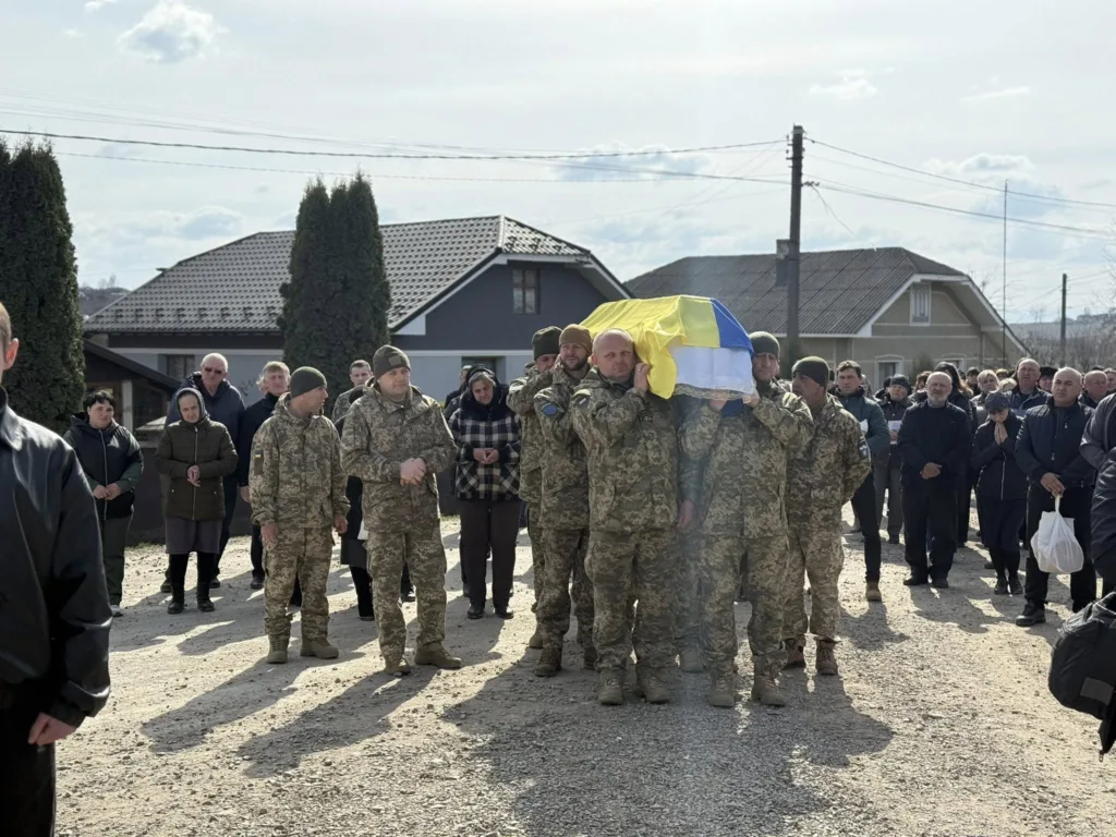 Військові несуть труну, накриту прапором України