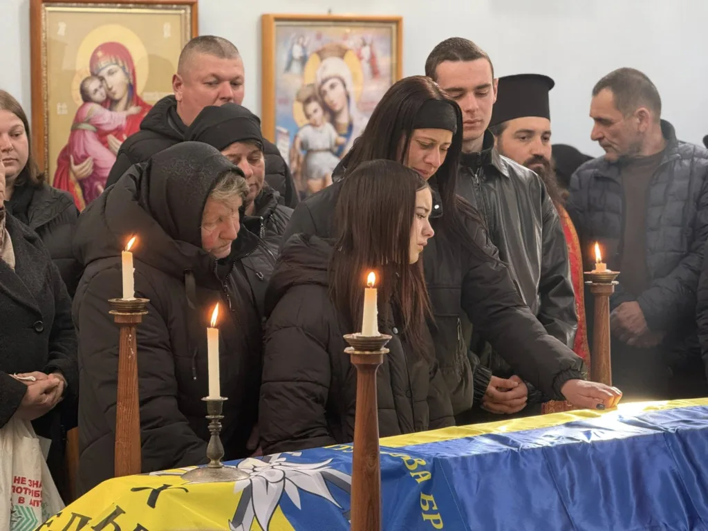 Люди прощаються з військовим під українським прапором