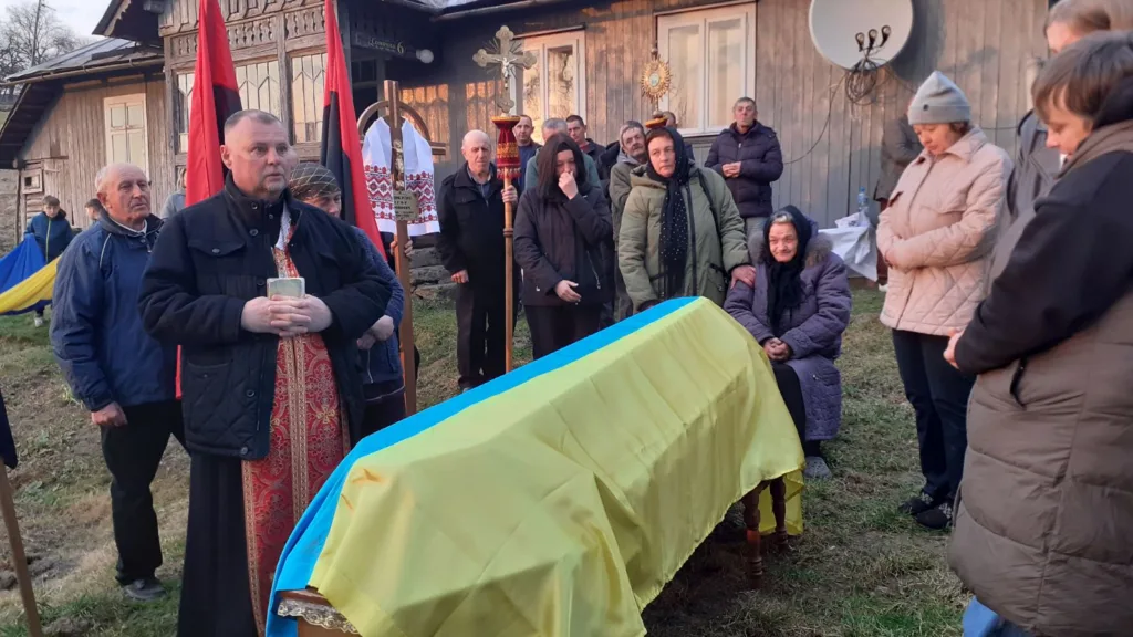 Похоронна церемонія з труною, накритою українським прапором