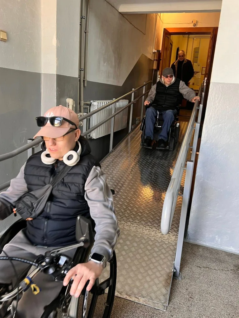 Люди на інвалідних візках спускаються пандусом