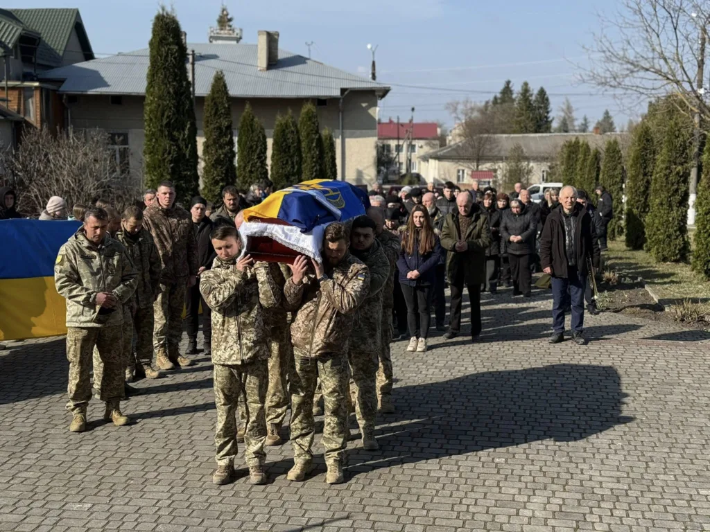 Військові несуть труну під українським прапором
