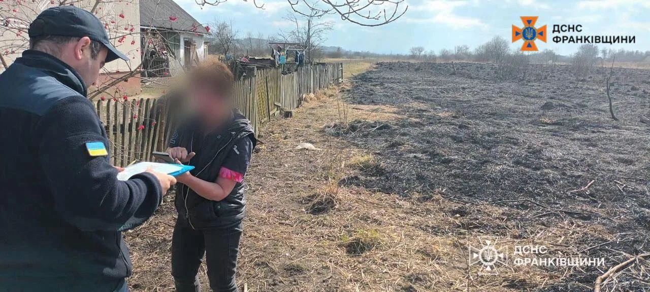 Рятувальник спілкується з жінкою після польової пожежі