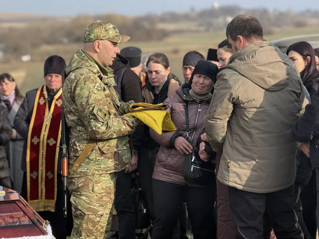 Військовий передає прапор родині загиблого героя