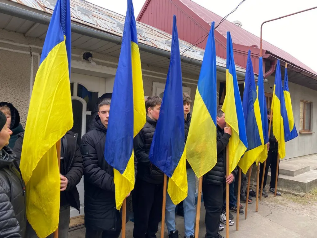 Люди тримають прапори України перед будинком