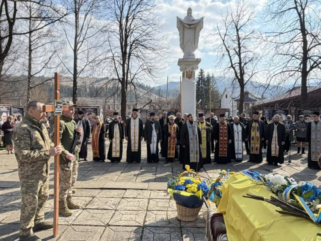 Військовий похорон із священниками та українським прапором
