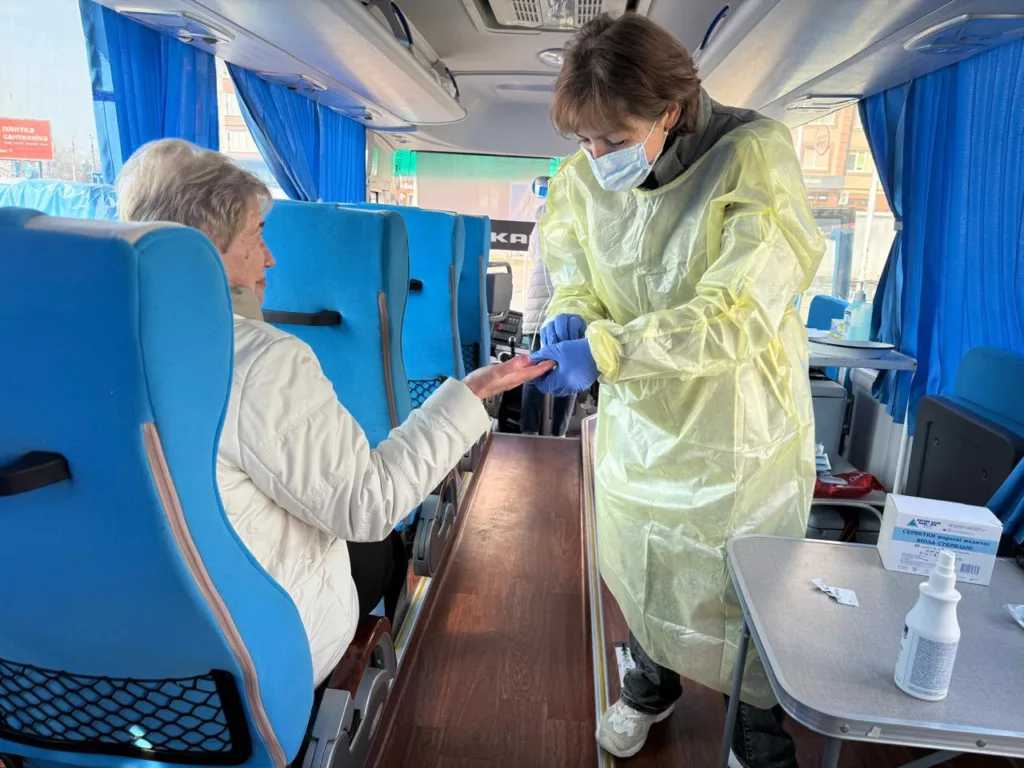 Медик оглядає пацієнтку в мобільному медпункті