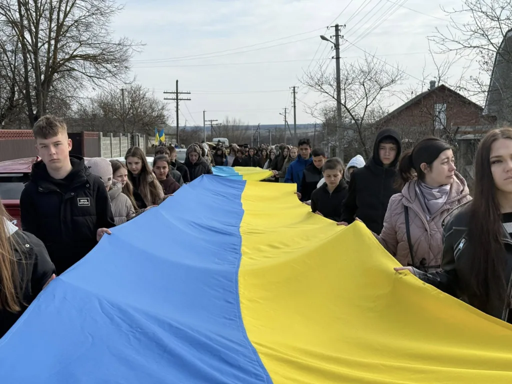Люди несуть великий прапор України на вулиці