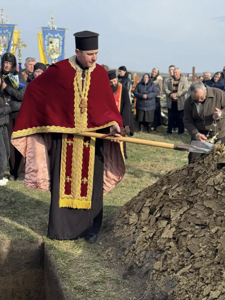 Священник проводить похоронну церемонію на кладовищі
